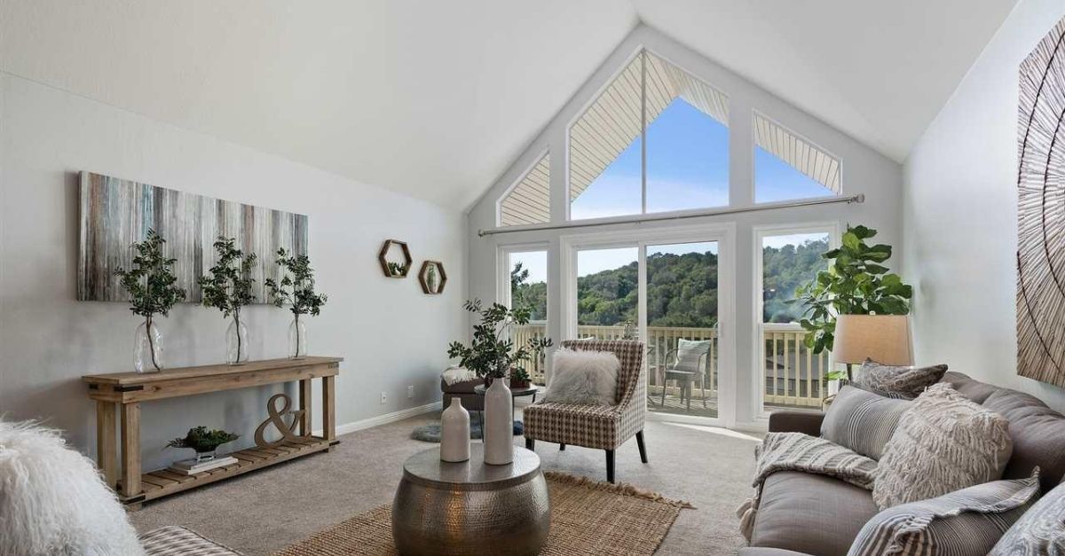 Interior of condo for sale in Moraga, California with large windows, staged furniture and balcony 