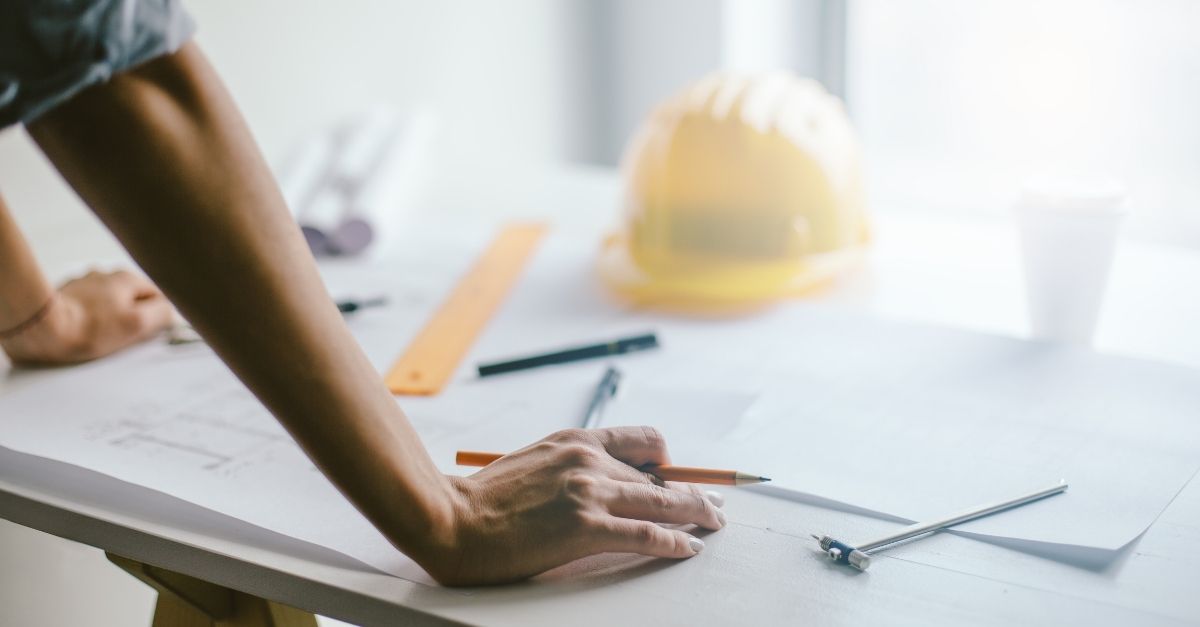 Person viewing a floor plan for a house with a hard hat