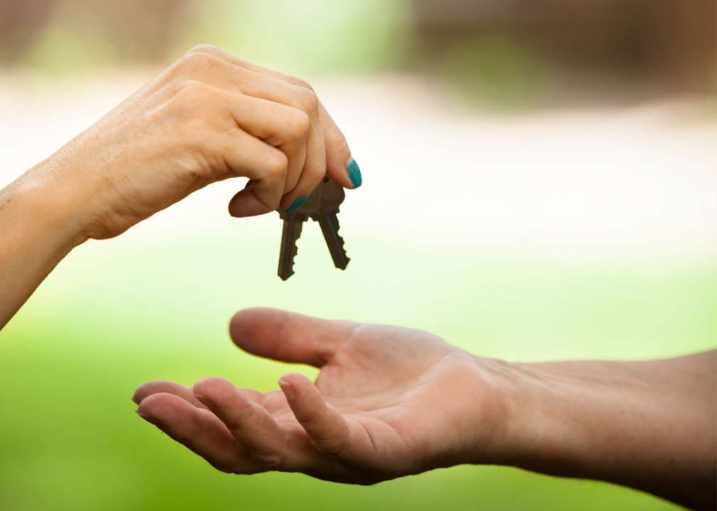 Hand with painted nails handing keys to another hand