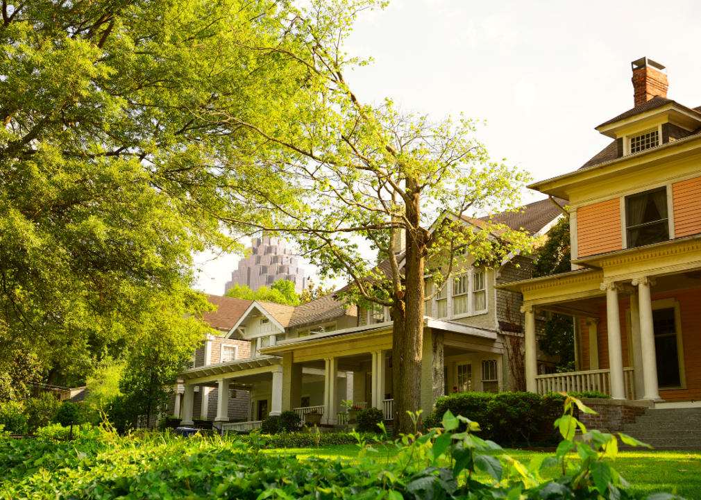 Historic homes with green lawns and a skyscraper in the distance.