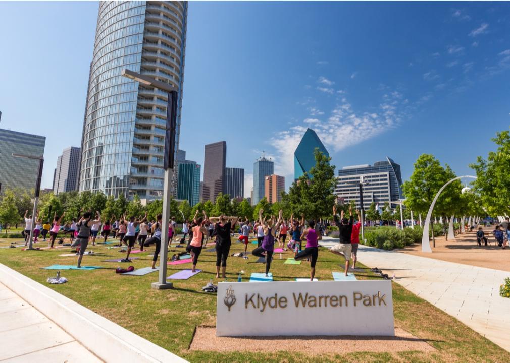 People doing yoga near buildings and art.